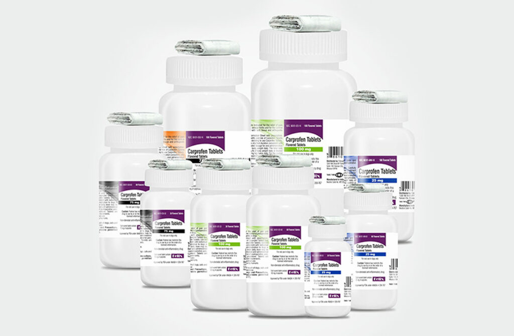 An assortment of Carprofen Tablets medication bottles for dogs in a variety of sizes and dosages stacked together.