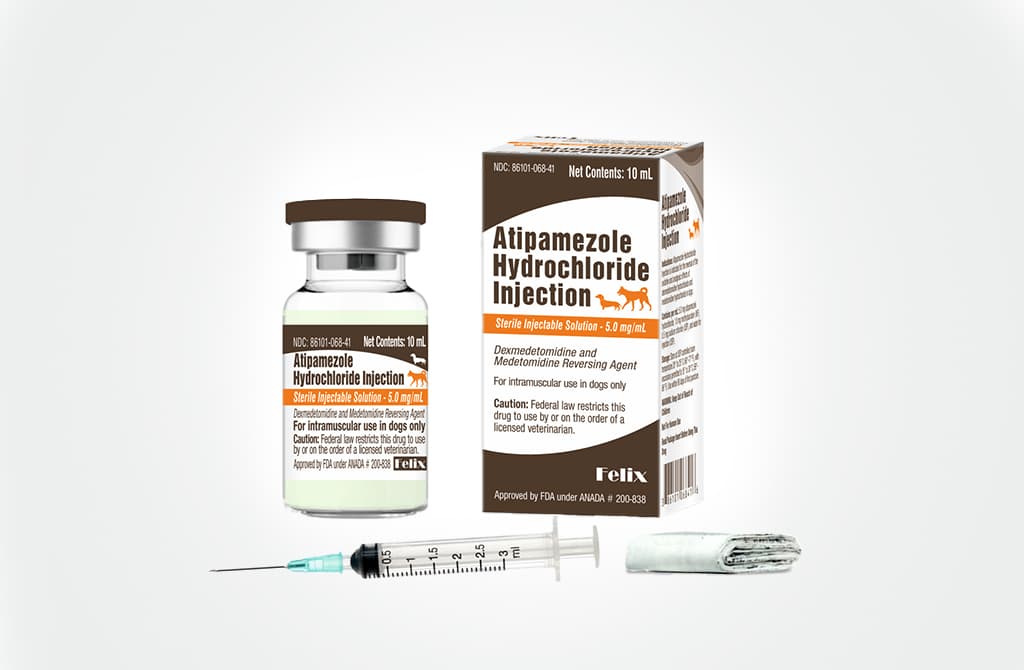 A 10 mL glass vial and the packaging box for Atipamezole Hydrochloride Injection with a small medical syringe and a folded product insert resting in front of the vial and packaging box.
