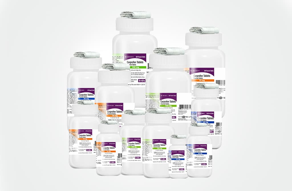 An assortment of Carprofen Tablets medication bottles for dogs in a variety of sizes and dosages stacked together.